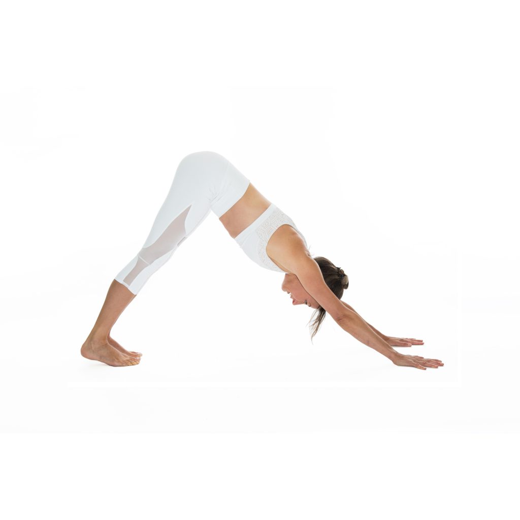 woman practices downward facing dog 
