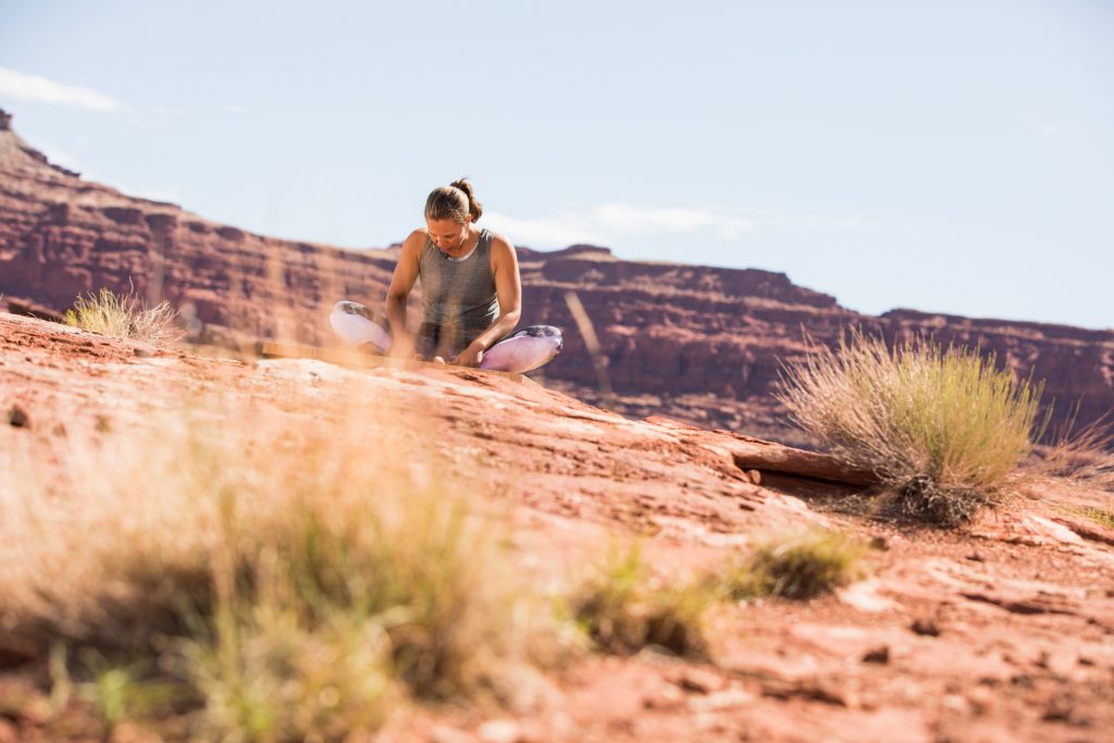 woman prepares fro meditation with a yoga pose while seated in the Utah dessert