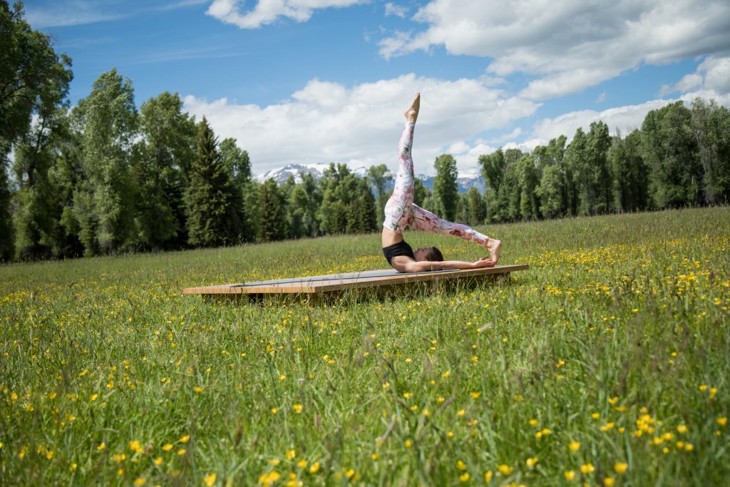 Pilates instructor works on her core while stretching her hamstrings. -yogatoday