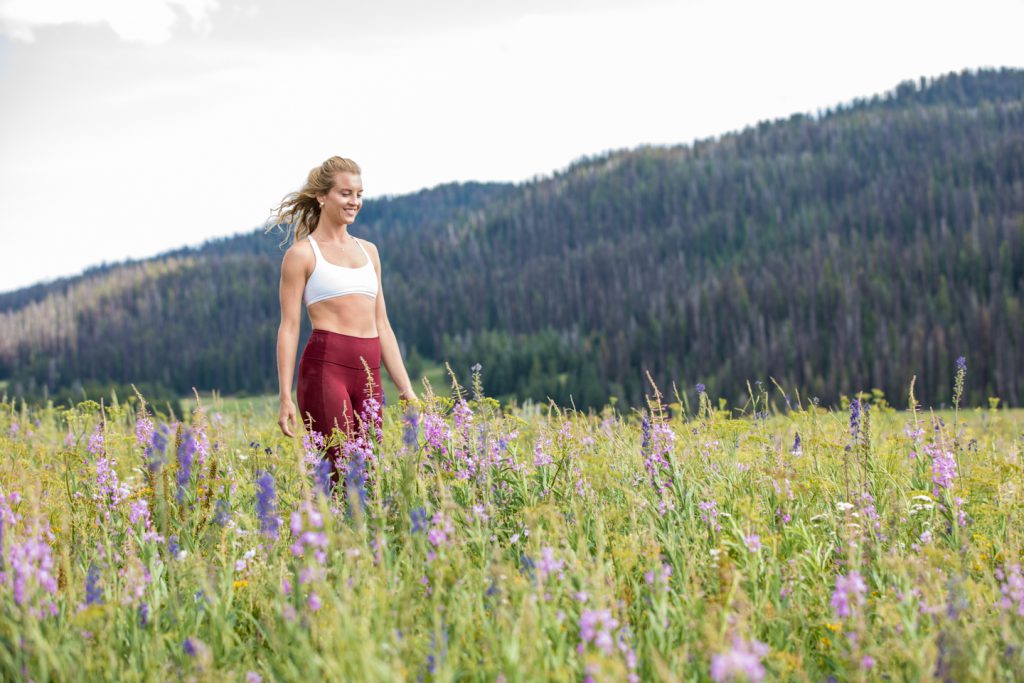 woman walks through a meadow of spring flowers -yogatoday