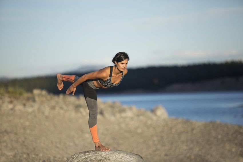woman practices warrior 3 yoga pose outdoors -YogaToday