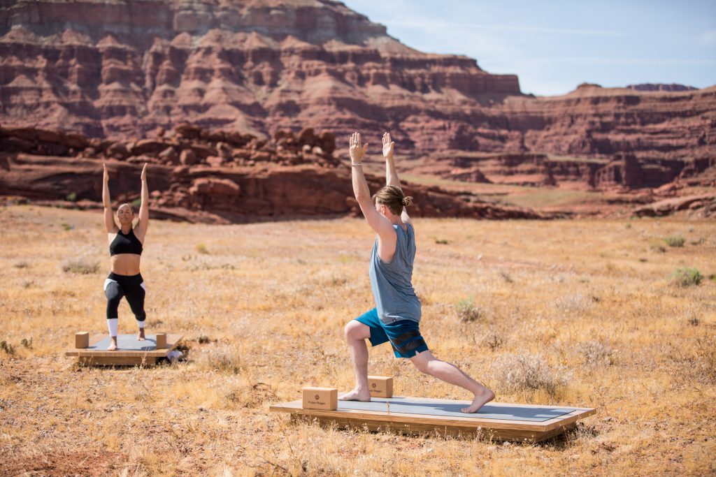 yoga teacher and student practice high lunge pose - yogatoday