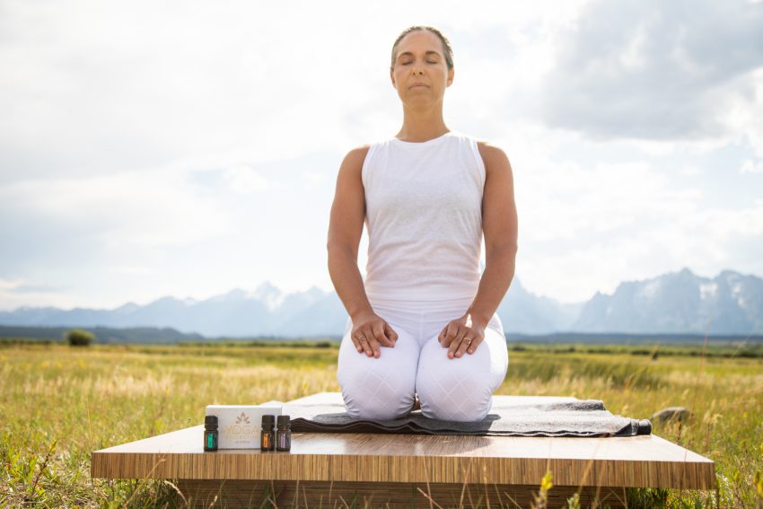 woman practices yoga outdoors with essential oils - yogatoday
