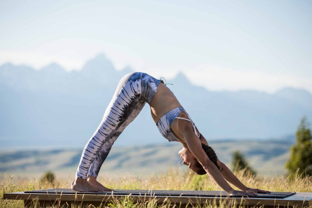 yogi practices downward dog pose outdoors - yogatoday