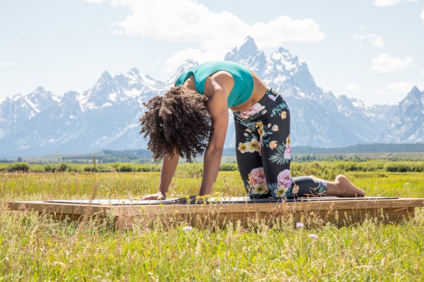 woman practices cat cow pose outdoors in Grand Teton National Park - YogaToday