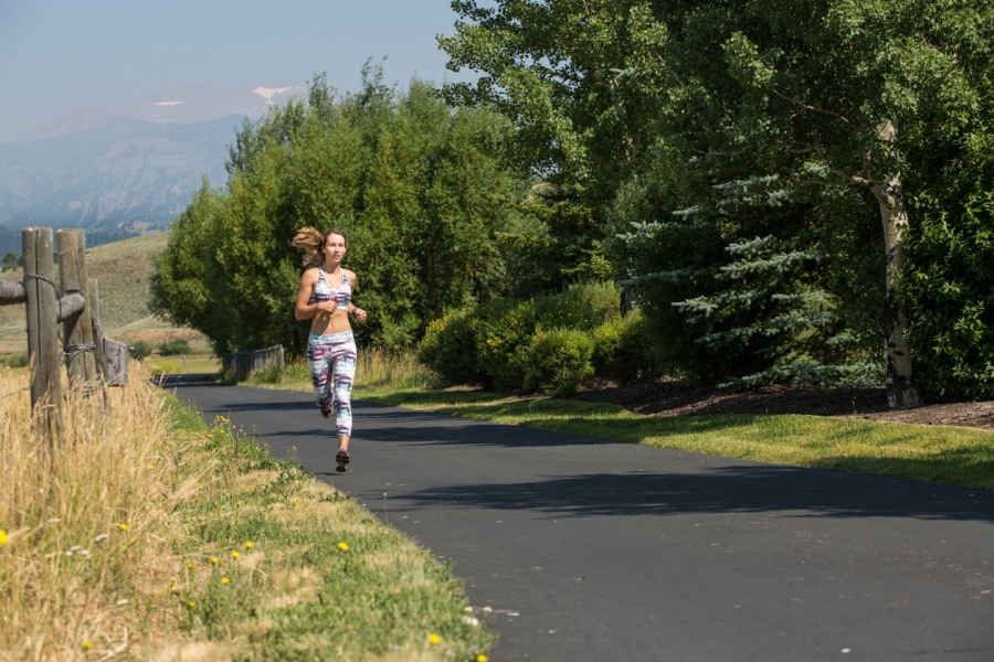 woman runs on a wooded path in Jackson Hole Wyoming - yogatoday