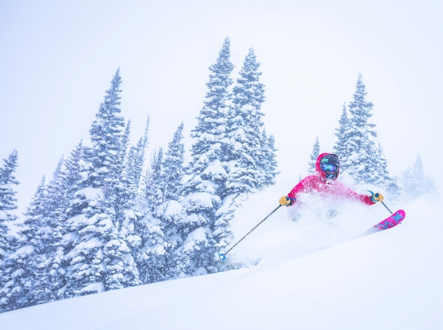 woman in a pink jacket skiing fresh powder in Jackson Hole Wyoming - yogatoday