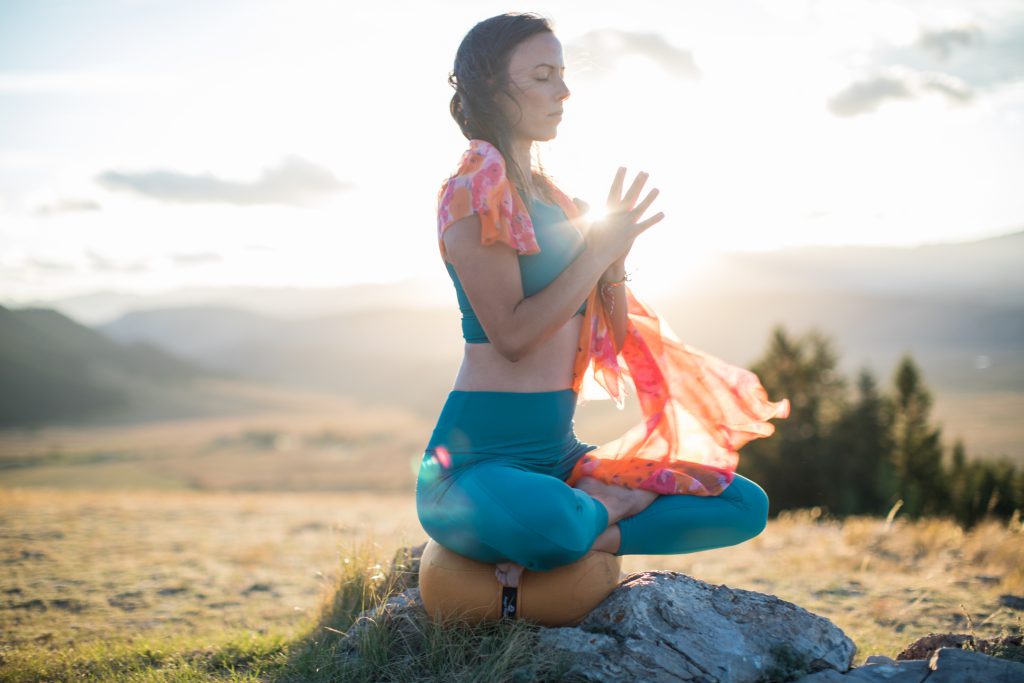 a woman meditates outdoors in Grand Teton National Park.