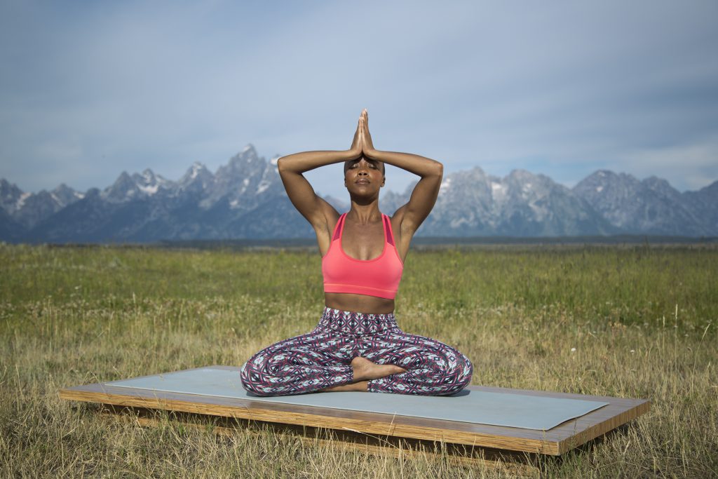 woman meditates with her hands in prayer at her third eye