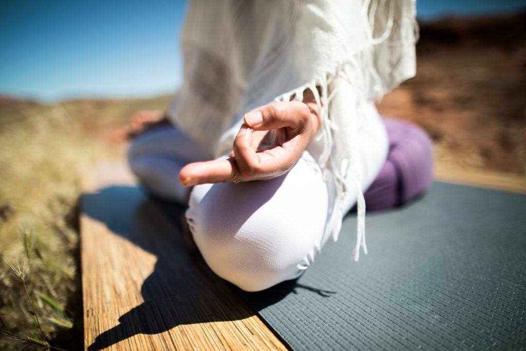 woman sits on yoga bolster while meditating