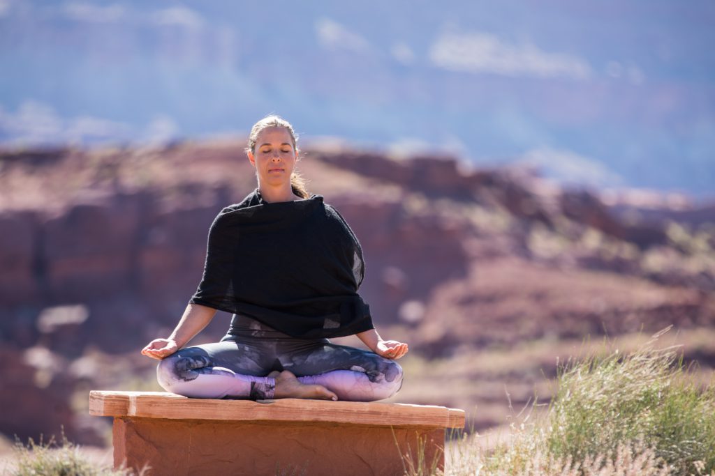 woman sits in meditation in Moab, Utah -yogatoday