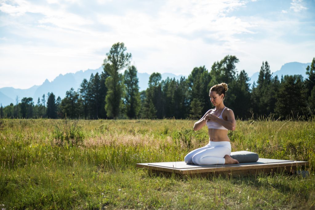 woman sits outside in meditation to stimulate the vagus nerve -yogatoday