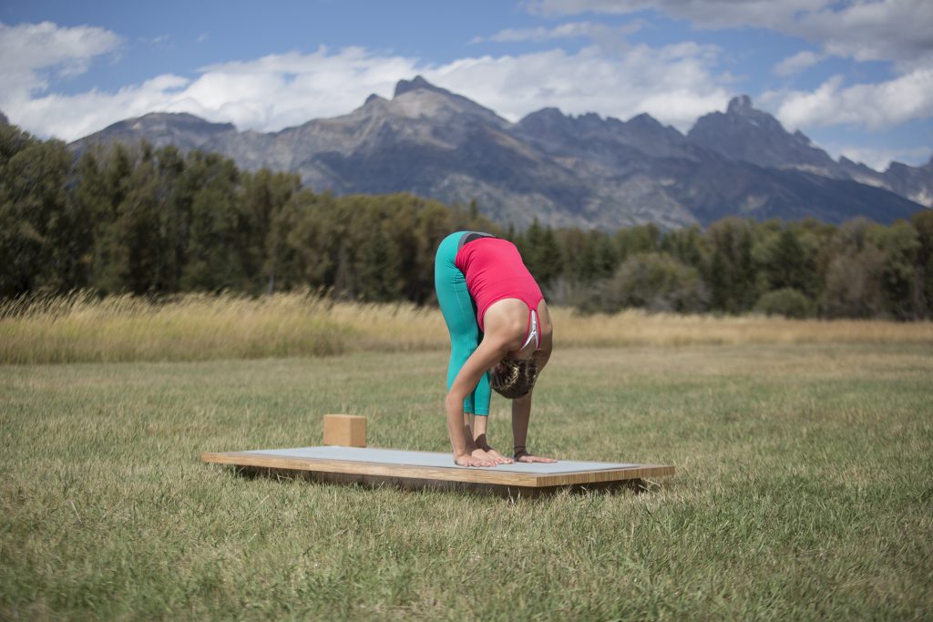 woman practices standing forward bend to relieve stress - yogatoday