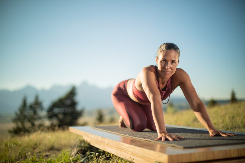 yoga teacher stretches on outdoor platform - yogatoday