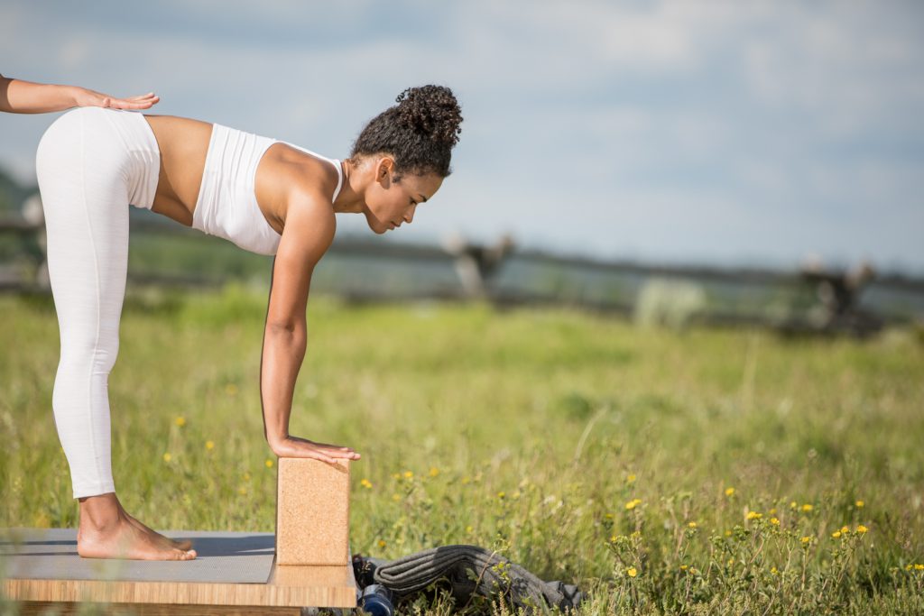 yoga student practices standing forward fold with yoga blocks