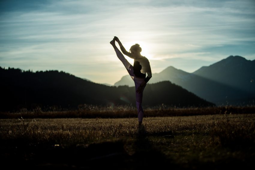 woman practices yoga outdoors in Fall season - YogaToday